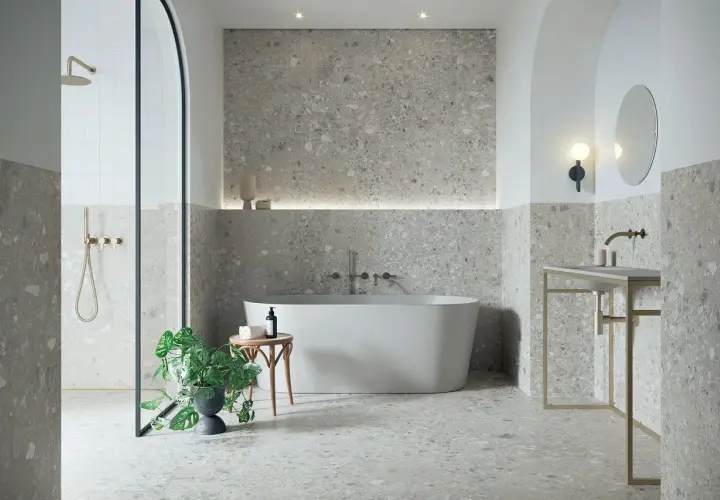 Modernes Badezimmer mit Terrazzo-Fliesen. Der Fliesentrend für Bäder zeigt sich hier in stilvoller Optik mit freistehender Wanne und Dusche.