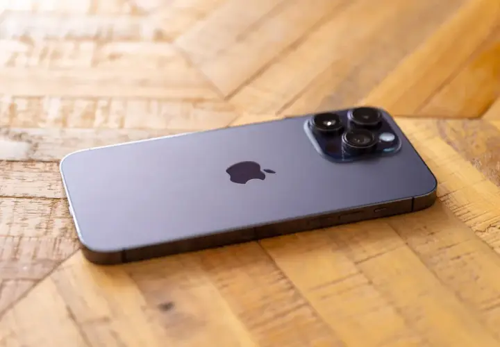 Nowy iPhone 14 Pro Max aparat z trzema obiektywami na drewnianym tle.
