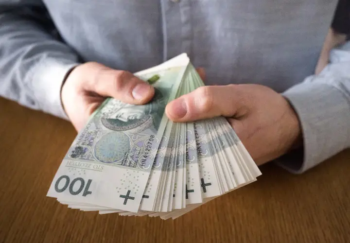Dłonie trzymające plik banknotów 100 zł. Czy to symbol najlepiej płatnych zawodów?