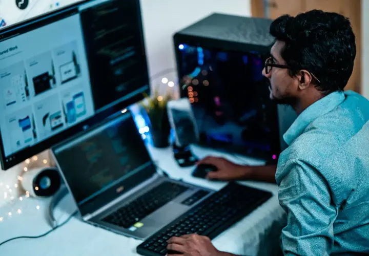 Un homme concentré sur ses écrans, le bon distance ecran yeux pour coder.