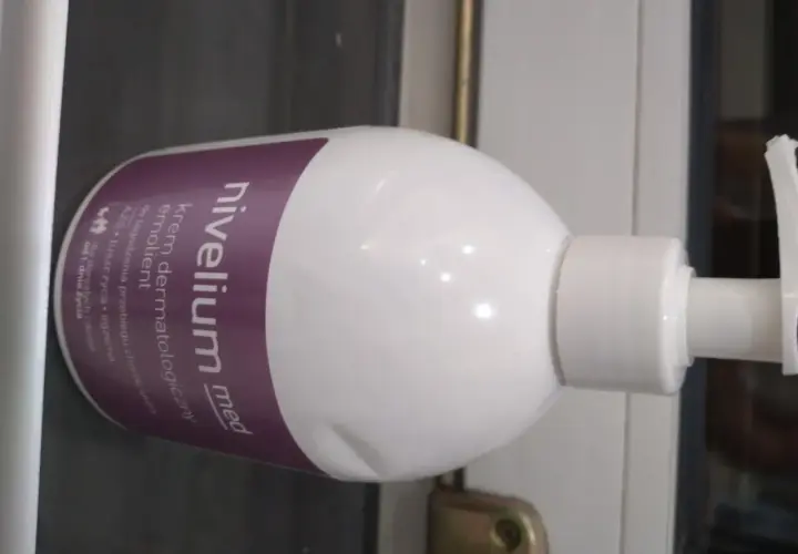 Biała butelka z pompką, na której widnieje napis "nivelium med krem dermatologiczny".