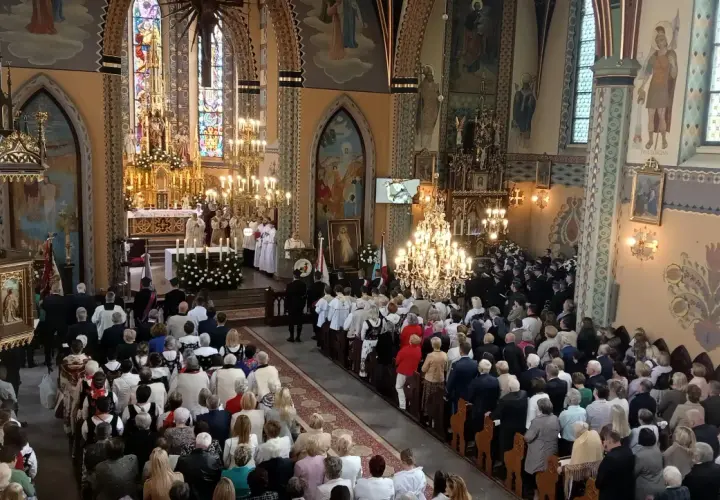 Uroczystość w kościele z wiernymi i duchownymi przy ołtarzu.