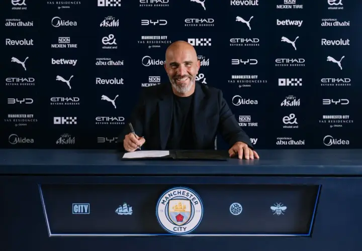 Uśmiechnięty trener Manchesteru City podpisuje kontrakt.