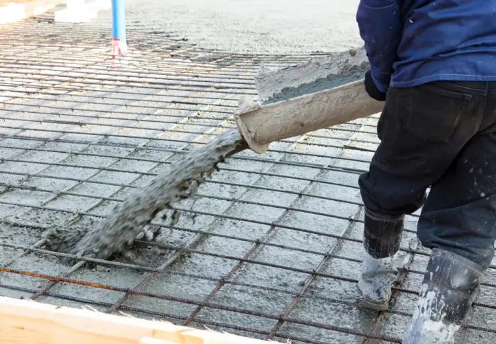 Betoniarz wylewa beton na zbrojenie, które zawiera włókna polipropylenowe, tworząc solidną posadzkę.