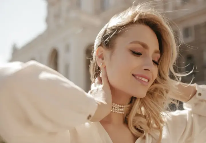 Uśmiechnięta blondynka z perłowym naszyjnikiem. Rozmiar naszyjnika idealnie podkreśla jej szyję.