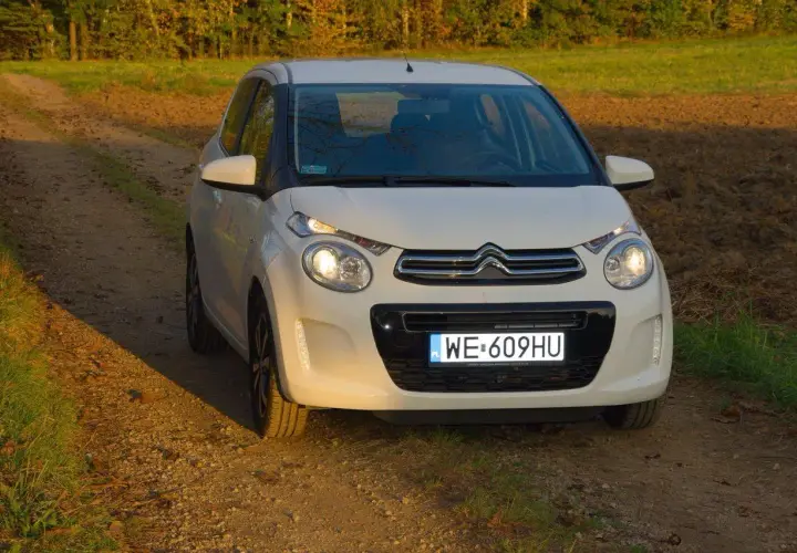 Biały Citroen C1 na tle jesiennego krajobrazu, na drodze gruntowej.
