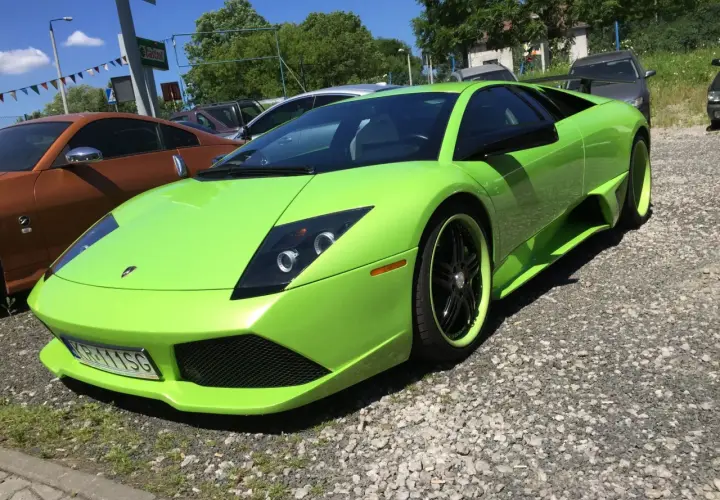 Jaskrawozielony Lamborghini Murcielago z czarnymi felgami i zielonymi akcentami stoi na żwirowym podjeździe.