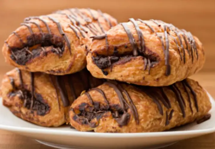 Cuatro napolitanas de chocolate apiladas en un plato blanco, con un glaseado de chocolate oscuro.