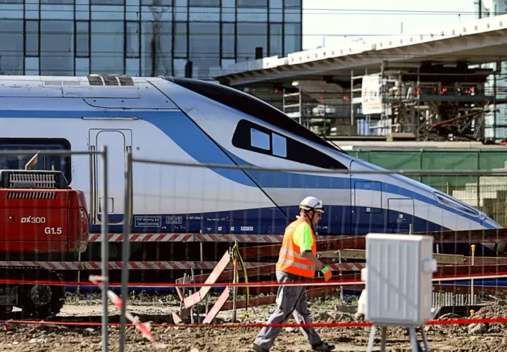 Budowa stacji, pracownik w kamizelce odblaskowej przechodzi obok pociągu Pendolino. Ile jedzie pociąg z Krakowa do Kołobrzegu?