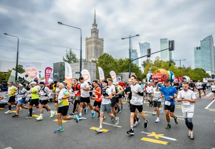 Uczestnicy biegną w maratonie, pokonując jego długość. W tle Pałac Kultury i Nauki.