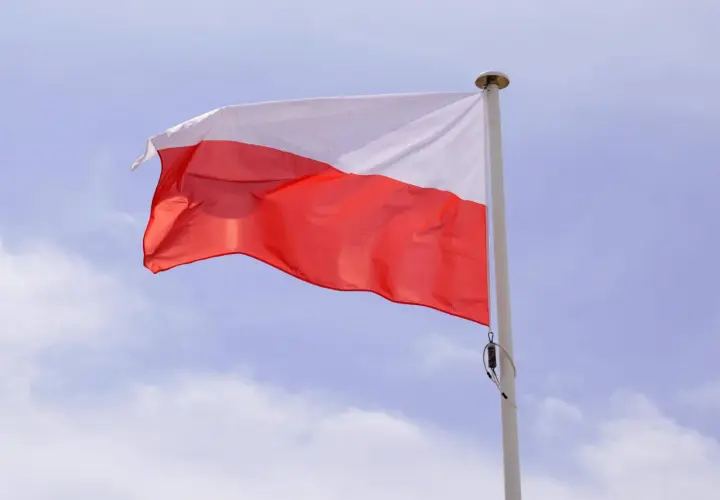 Biało-czerwona flaga powiewa na maszcie. Duma i symbole narodowe Polski w błękitnym niebie.