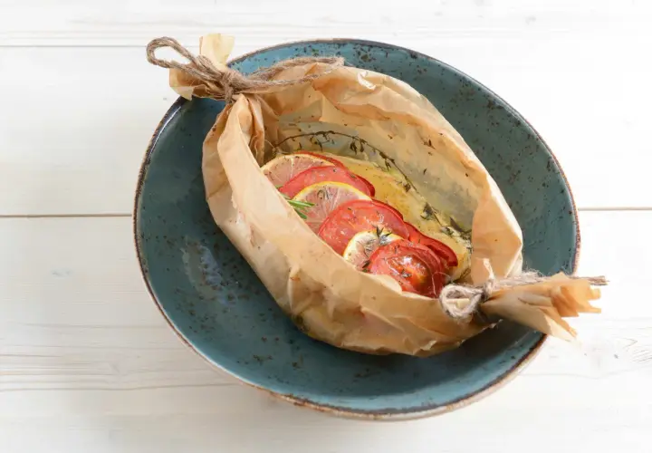 Bar au barbecue en papillote, garni de rondelles de tomates et de citron, prêt à être dégusté.