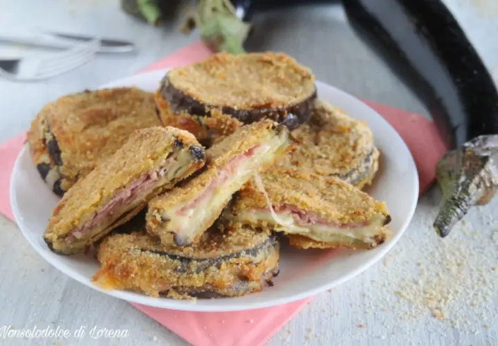 Cordon bleu di melanzane impanati e fritti, ripieni di prosciutto e formaggio filante, serviti su un piatto bianco.