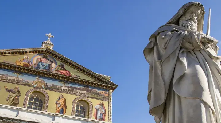Statua imponente e facciata decorata con mosaici a San Paolo fuori le Mura. Curiosità: ogni mosaico racconta una storia biblica.