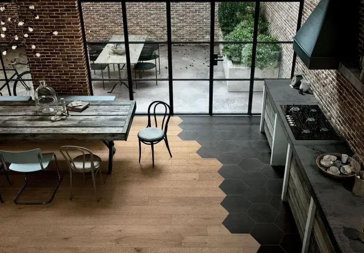 Un'elegante cucina con pavimenti che uniscono il calore del **parquet** e il design moderno delle **maioliche** esagonali scure.