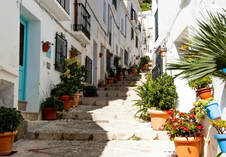Calle empedrada con escaleras y casas blancas adornadas con macetas. Un ejemplo de los pueblos bonitos cerca de Vera.