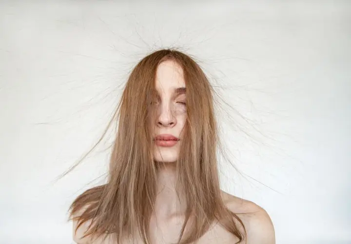 Frau mit langen Haaren, die elektrisch aufgeladen abstehen.