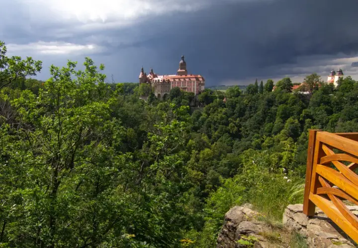 Zamek Książ góruje nad bujną zielenią, zapowiadając burzę. Widok z tarasu widokowego w Książańskim Parku Krajobrazowym.