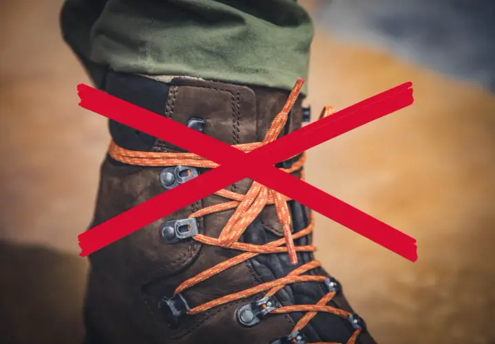 A red X crosses over a brown hiking boot with orange laces. The question "why are boot laces so long?" is implied.