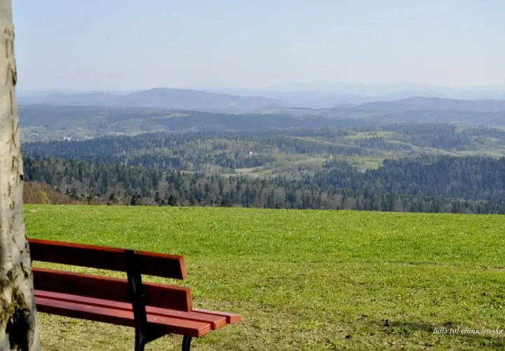 Ławka na tle malowniczego krajobrazu z lasami i pagórkami. Widok z szybowiska Bezmiechowa zapiera dech w piersiach.