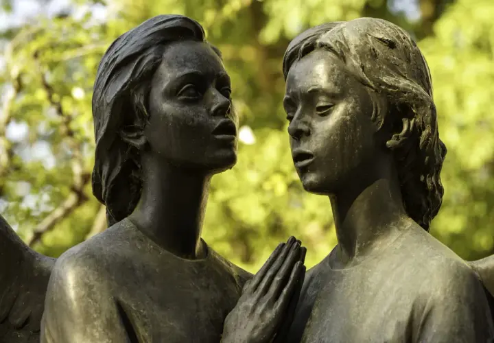 Deux anges en bronze, œuvre d'un fondeur d'art, se regardent tendrement. Leurs mains jointes évoquent une prière silencieuse.