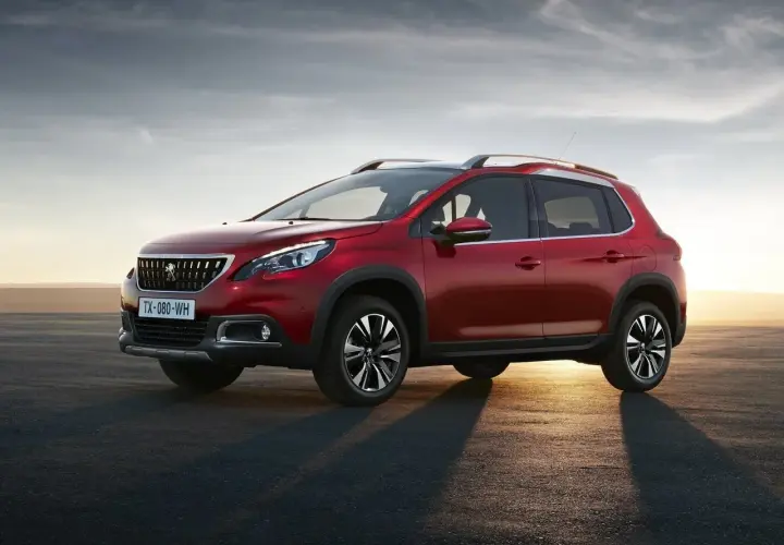 Czerwony Peugeot 2008 na tle zachodzącego słońca. Wiele osób szuka peugeot 2008 opinie przed zakupem.