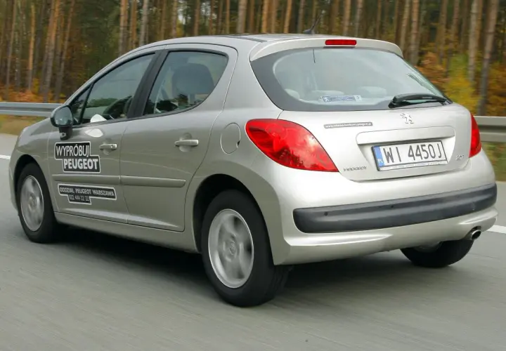 Srebrny Peugeot 207 1.4 benzyna w ruchu drogowym. Na drzwiach naklejka "Wypróbuj Peugeot".