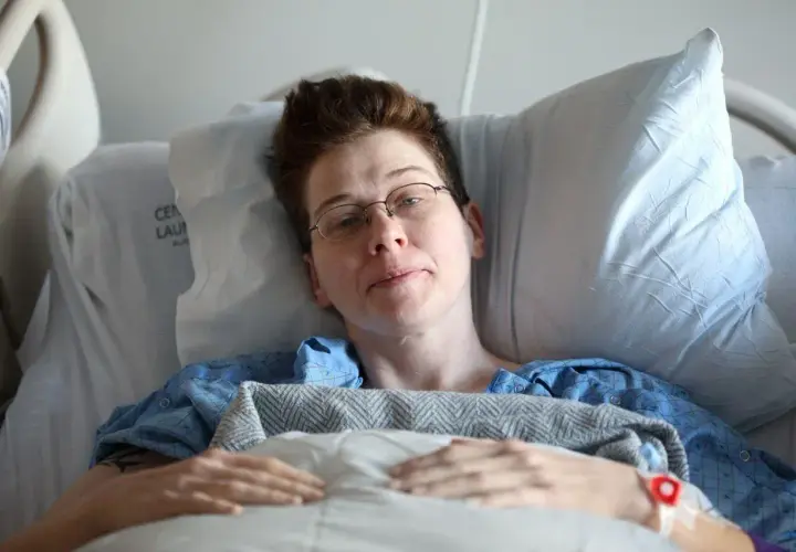Osoba w szpitalnym łóżku, w niebieskiej koszuli, z opaską na ręce. Może to być obraz symbolizujący potrzebę zadośćuczynienia za szkody psychiczne.