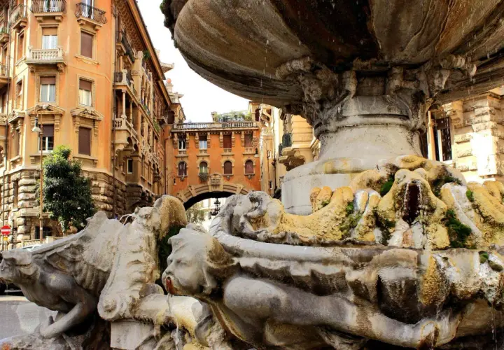 Fontana barocca a Roma Nord, con palazzi storici sullo sfondo e acqua che scorre tra le sculture.