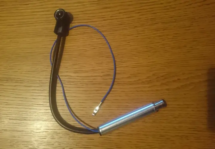 Antena samochodowa z kablem i wtyczką na drewnianym tle.
