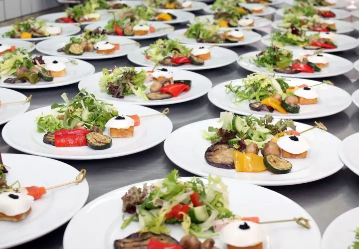 Organisation buffet : assiettes individuelles de salade fraîche, légumes grillés et amuse-bouches joliment dressés, prêts à être servis.