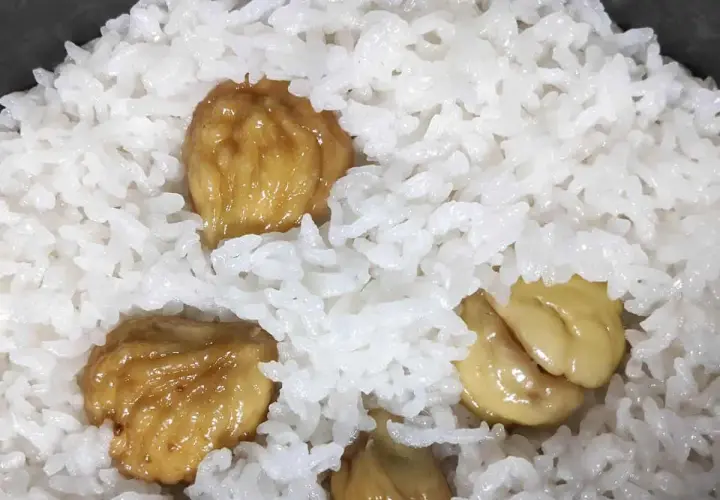 A close-up of fluffy white rice with sweet, glazed chestnuts scattered throughout. This chestnut rice looks delicious and comforting.