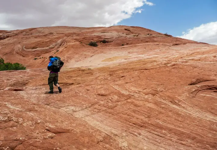 Wanderer auf rotem Felsplateau, wo die Moqui Marbles sich bewegen.