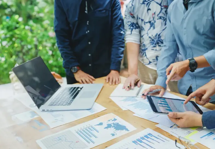 Team discute grafici e dati su un tavolo all'aperto, pianificando i loro buoni propositi per il futuro.