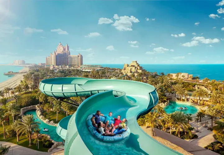 Familie hat Spaß im Dubai Wasserpark auf einer Rutsche, mit dem Atlantis Hotel im Hintergrund.