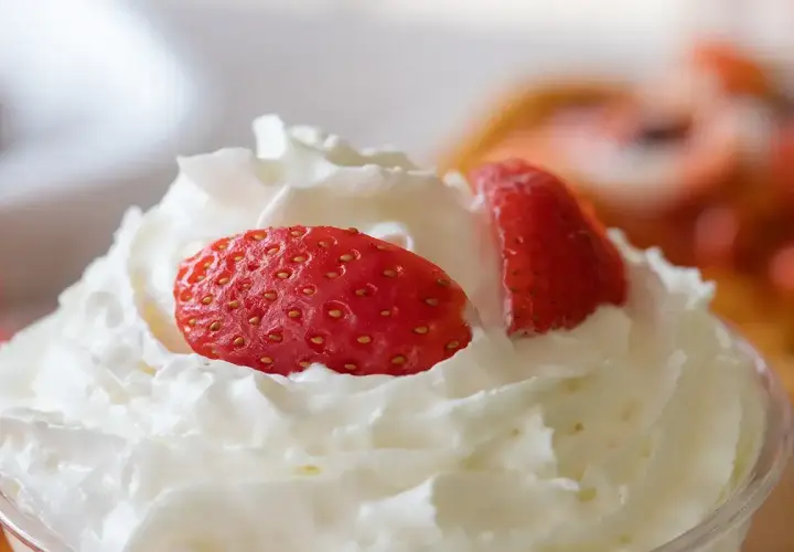 Chantilly aérienne garnie de fraises fraîches. Une invitation à découvrir comment faire de la chantilly maison pour un dessert parfait.