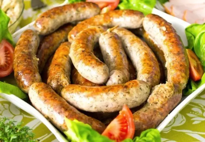 Pyszna biała kiełbasa surowa, idealna do pieczenia. Podana z sałatą i pomidorem.