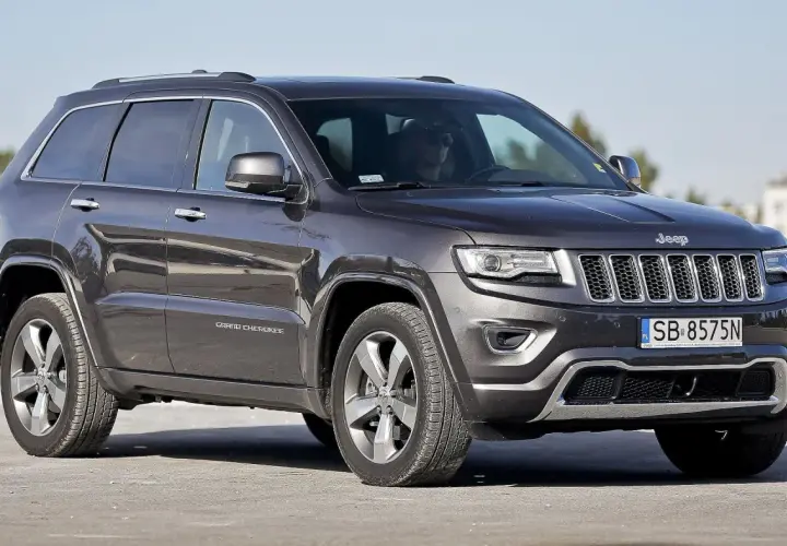 Ciemnoszary Jeep Grand Cherokee WK2 z polskimi tablicami SB 8575N zaparkowany na zewnątrz.