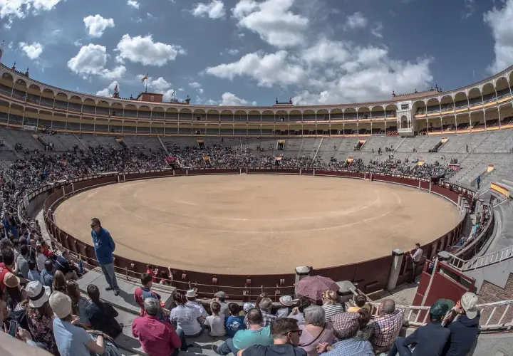 Espectadores en la plaza de toros, la plaza más grande de España, bajo un cielo azul con nubes.