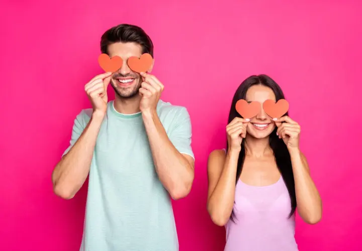 Coppia sorridente con cuori rossi sugli occhi, un modo giocoso per scoprire trucchi psicologici per capire se gli piaci.