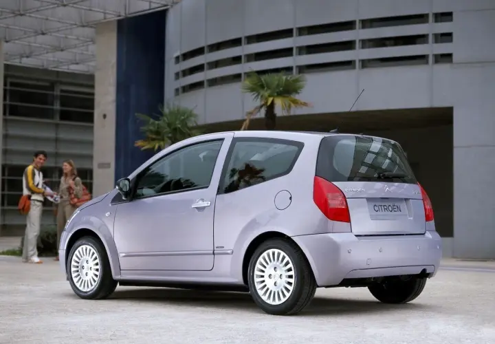 Jasnoszary Citroën C2 z parą na tle nowoczesnego budynku.