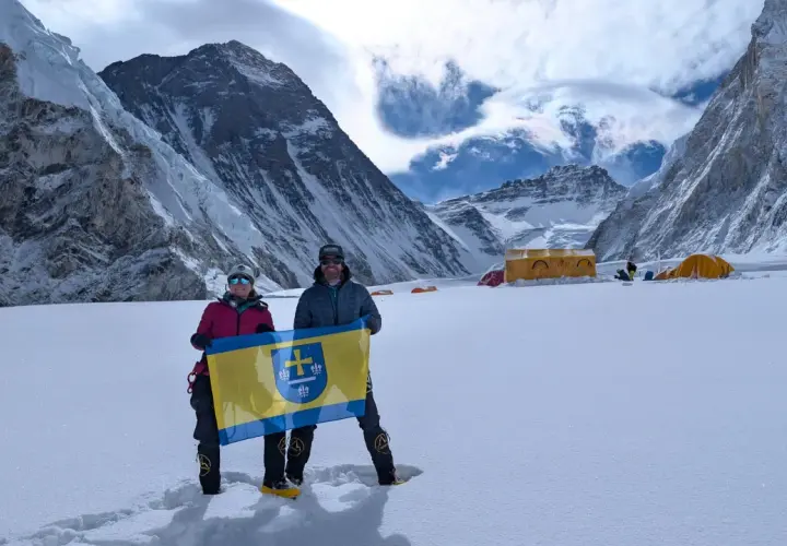 Polacy na Mount Everest dumnie prezentują flagę na tle majestatycznych gór. W tle widoczne namioty obozowe.
