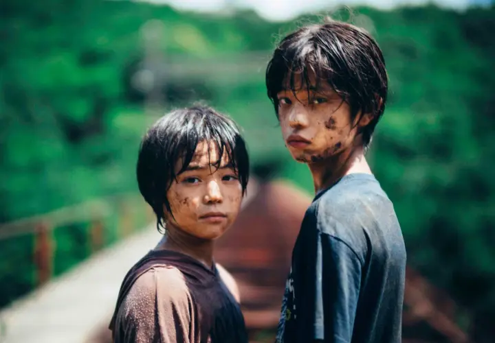 Due ragazzini sporchi di terra, con sguardi intensi, sembrano usciti da un film di mostri. Le loro espressioni suggeriscono storie che meritano recensioni.