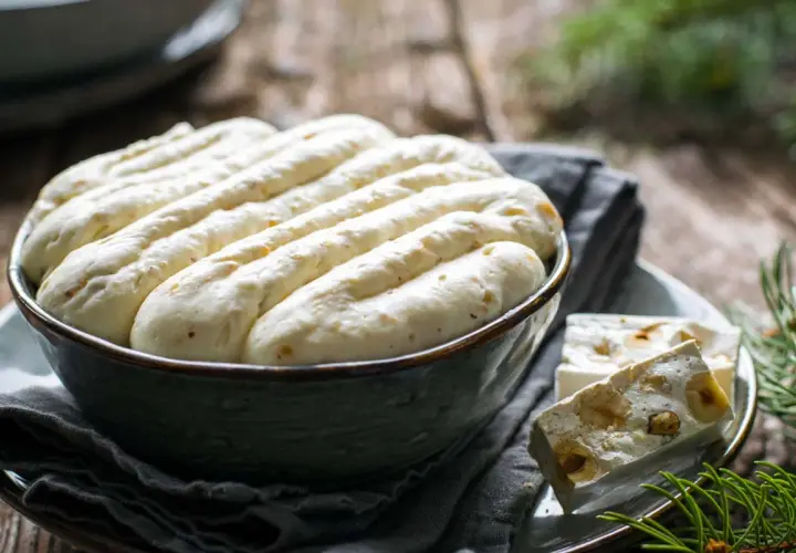 Crema torrone soffice in ciotola, con pezzi di torrone alle nocciole accanto.