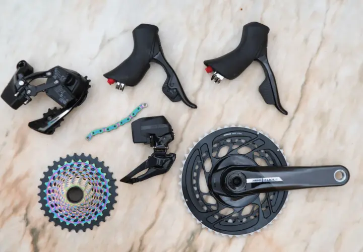 SRAM news: A new Force AXS groupset with rainbow cassette, crankset, derailleurs, and shifters laid out on a marble surface.