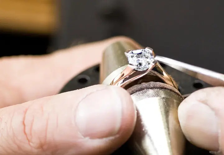 Ein Juwelier setzt einen funkelnden Diamanten, einen kostbaren Edelstein, in eine Ringschiene ein.