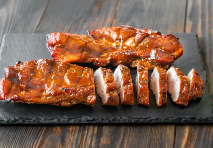 Soczyste, glazurowane żeberka wieprzowe, pokrojone na kawałki. Idealne do grillowania, zastanawiasz się, jak długo wędzić polędwiczki wieprzowe, by osiągnąć taki efekt?