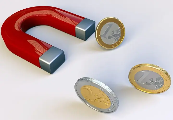 Czerwony magnes podkowowy przyciąga monety euro.