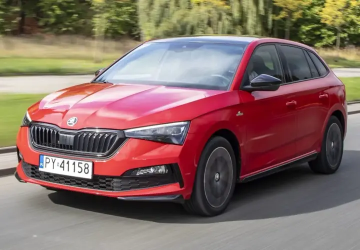 Czerwona Skoda Scala Monte Carlo pędzi po drodze, błyszcząc w słońcu.