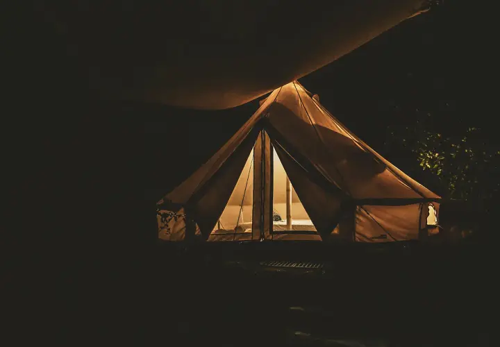 Nocne darmowe pola namiotowe. Oświetlony namiot tipi w ciemności, zapraszający do odpoczynku.